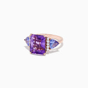 The 14K Rose Gold Amethyst, Tanzanite and Diamond Ring (7.49 TCW) showcases a large rectangular amethyst center, two triangular tanzanites, and four round diamonds on each side, all set against a white background.