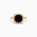 The 14K Yellow Gold Garnet and Diamond Ring features a cushion-cut deep red garnet center, surrounded by a halo of baguette and round white diamonds, with more diamonds set along the band.
