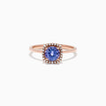 The Nahla Siri 14K Rose Gold Tanzanite and Diamond Ring (0.81 TCW) showcases a cushion-cut blue tanzanite encircled by a halo of clear diamonds, set against a white background.