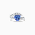 The Nahla Siri 14K White Gold Tanzanite and Diamond Ring, 1.88 TCW, showcases a large triangular blue tanzanite center with a curved band of round diamonds above it, set in an elegant modern design.