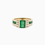 The Brasilica 14K Yellow Gold Emerald and Diamond Ring, 2.26 TCW, showcases a large rectangular emerald center with three round diamonds on each side and extra green stones set along the band for added elegance.