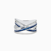 The 14K White Gold Blue Sapphire and Diamond Crossover Ring features overlapping bands adorned with sparkling diamonds and vivid blue sapphires in an elegant crisscross design, shown on a white background.
