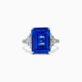 The 14K White Gold Tanzanite and Diamond Cocktail Ring, 7.83 TCW, features a large rectangular blue tanzanite with step-cut facets, accented by geometric clusters of sparkling diamonds on each side, showcased against a white background.