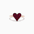 The 14K Rose Gold Ruby Heart Ring showcases a heart-shaped centerpiece with red gemstones, casting a gentle shadow on a white background.