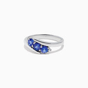 The Nahla Siri Sterling Silver Tanzanite and Diamond Ring (0.86 TCW) showcases three round tanzanites set side by side in a modern overlapping band, displayed on a white background.