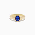 The Nahla Siri 14K Yellow Gold Tanzanite Ring features an oval-shaped deep blue gemstone in a simple bezel setting, shown against a white background.