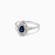 The Royale Bleu 14K Two Tone Gold Sapphire and Diamond Ring, 0.77 TCW, features a pear-shaped sapphire center with double diamond halos, gold accents, and a diamond-adorned band.