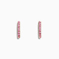 A pair of 14K yellow gold huggie hoop earrings, set with pink sapphires totaling 0.86 TCW, displayed against a white background.