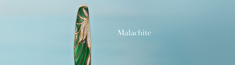 Close-up of a luxurious green malachite pen with gold and diamond accents on a soft blue background, with the word Malachite displayed to the right.
