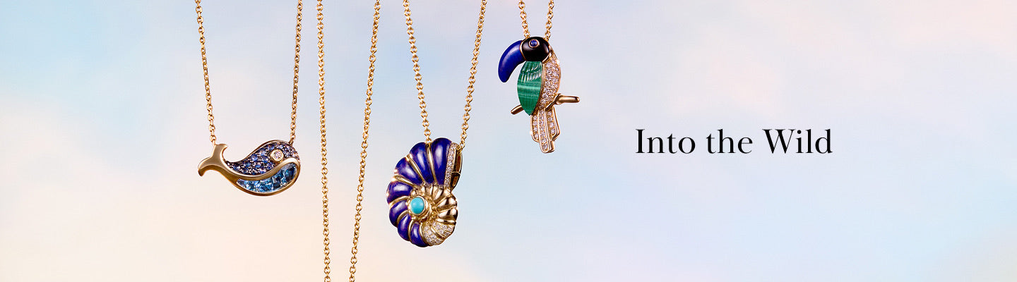 Four gold necklaces with animal and shell pendants—a dolphin, a seashell, and a toucan—hang against a pastel sky background with the text Into the Wild beside them.
