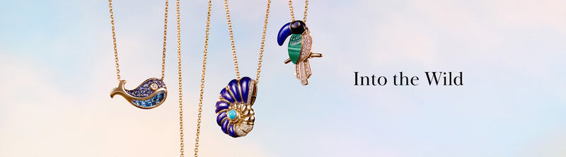 Four gold necklaces with animal and shell pendants—a dolphin, a seashell, and a toucan—hang against a pastel sky background with the text Into the Wild beside them.