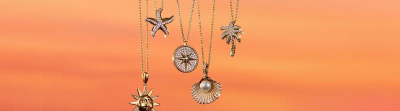 Three gold necklaces with diamond-studded sea-inspired pendants—a starfish, sand dollar, and palm tree—hang against a soft orange background. Text reads: The Vacation Edit.