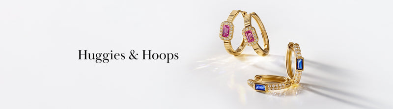 Two pairs of gold hoop earrings are displayed: one with pink gemstones and the other with blue gemstones and small clear stones, next to the text Huggies & Hoops.