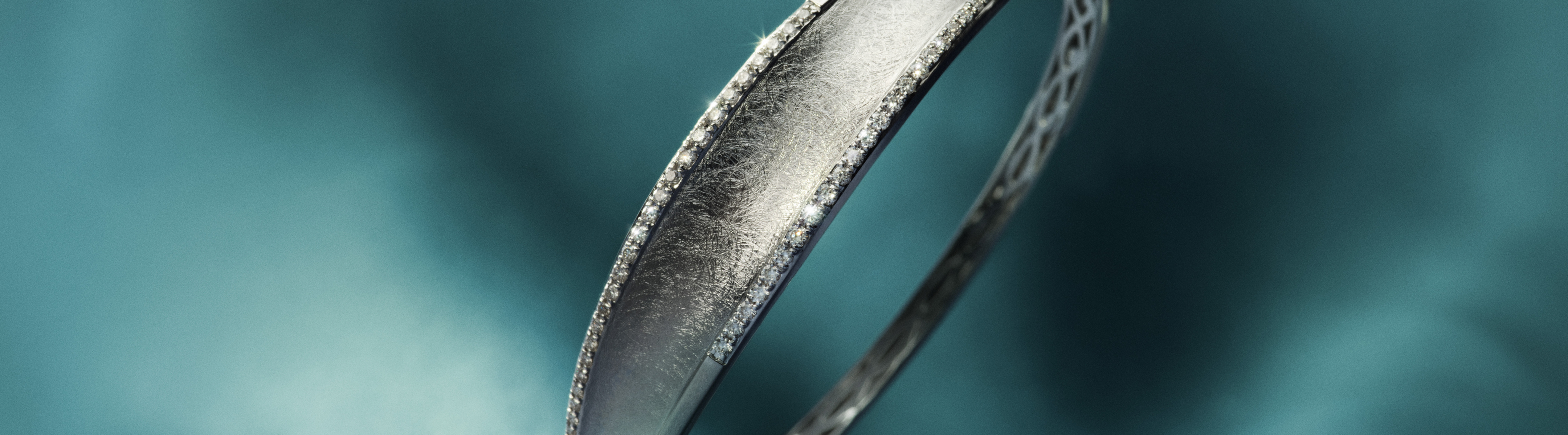 Three shiny silver rings, including a heart, a starburst design, and a textured band, rest on rippling water with a soft blue background. The word Silver appears on the right.
