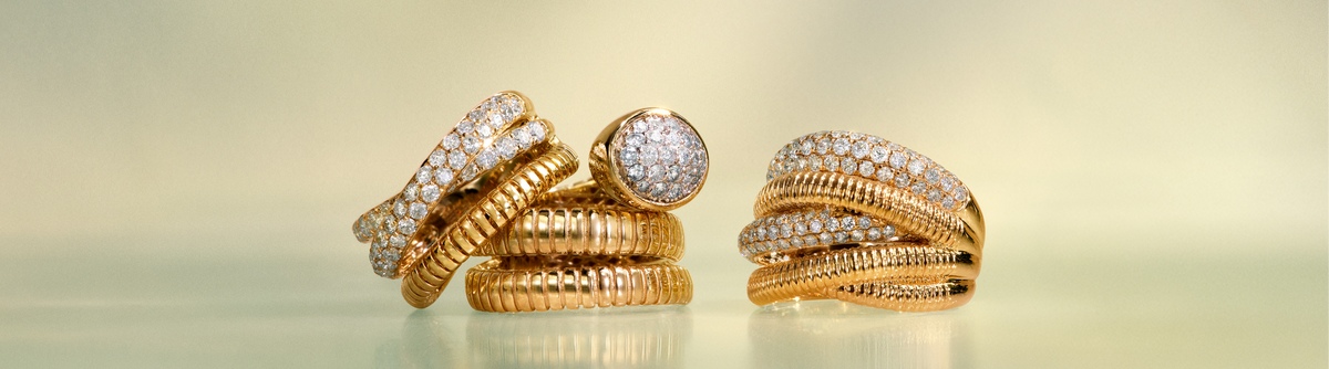 Gold earrings and a ring with diamond accents rest on folded sheet music and papers, creating an elegant, artistic arrangement in soft, warm lighting.