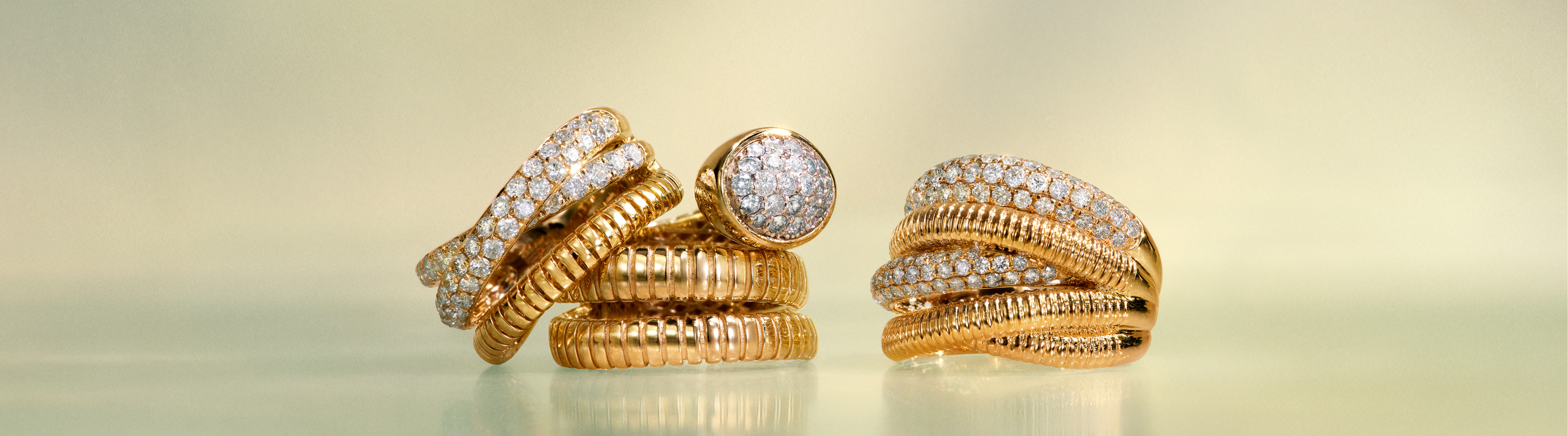 Gold earrings and a ring with diamond accents rest on folded sheet music and papers, creating an elegant, artistic arrangement in soft, warm lighting.