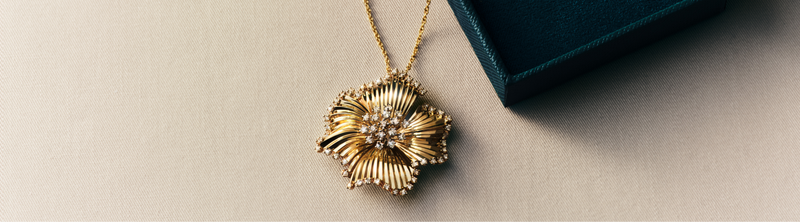 A gold bangle with interlocking bands rests on white tissue paper, next to the text DOro on a dark green background.