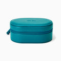 The Effy Oval Travel Case is a small, oval-shaped zippered case in teal vegan leather with a matching teal zipper, closed and displayed on a white background.