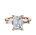 The 18K Rose Gold 3-Stone Baguette East/West Side Stones 0.125TCW Engagement Ring features a central diamond with two baguette side stones, beautifully displayed against a plain white background.