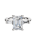 The 14K White Gold 3-Stone Baguette East/West Side Stones 0.125TCW Engagement Ring features a center stone flanked by baguette-cut side stones in a classic prong setting, displayed against a white background.