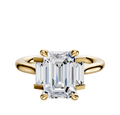 A 14K yellow gold engagement ring with a north/south set, featuring a main stone and baguette side stones (0.125TCW), displayed against a plain, light background.