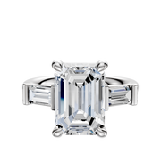The 18K White Gold 3-Stone Baguette East/West Side Stones 0.25TCW Engagement Ring features a central stone flanked by two baguette-cut diamonds, beautifully set against a white background.