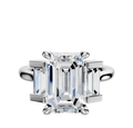An 18K white gold engagement ring with a three-stone north/south design featuring baguette side stones, totaling 0.25TCW, is displayed against a plain white background.
