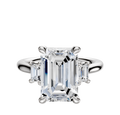 An 18K white gold engagement ring with a three-stone design, featuring an emerald-cut center stone and two rectangular side stones totaling 0.25TCW, set on a polished band.