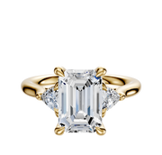 The 14K Yellow Gold 3-Stone Trillion Side Stones 0.125TCW Engagement Ring showcases a center diamond accented by two smaller trillion-cut side stones, all set on a polished gold band against a white background.
