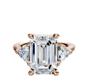 The 14K Rose Gold 3-Stone Engagement Ring features a center diamond accented by two trillion side stones, totaling 0.25TCW, all set in secure prongs.