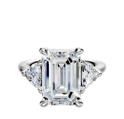 An 18K white gold engagement ring with a three-stone design, featuring 0.25TCW trillion side stones, displayed against a plain white background.