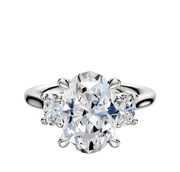 A 14K white gold engagement ring featuring a three-stone design with an oval center and side stones totaling 0.125TCW.