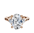 The 14K Rose Gold 3-Stone Trillion Side Stones 0.125TCW Engagement Ring showcases an oval center diamond with two triangular side stones, displayed on a plain white background.