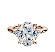The 18K Rose Gold 3-Stone Trillion Side Stones 0.125TCW Engagement Ring showcases a sparkling center diamond with two trillion-cut side stones, elegantly displayed on a plain white background.
