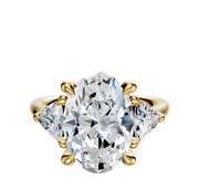 An 18K yellow gold engagement ring featuring a large center diamond and two trillion side stones (0.25TCW), displayed against a plain white background.