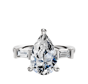 A 14K white gold engagement ring with a three-stone design, featuring east/west baguette side stones totaling 0.125TCW, displayed against a plain white background.