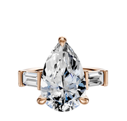 The 14K Rose Gold 3-Stone Baguette East/West Side Stones 0.25TCW Engagement Ring features a pear center stone flanked by rectangular baguette diamonds, all set against a plain white background.