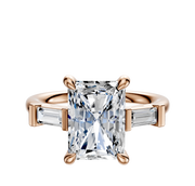 The 18K Rose Gold 3-Stone Baguette East/West Side Stones 0.125TCW Engagement Ring showcases a radiant-cut center diamond with two tapered baguette side stones, elegantly set against a plain white background.