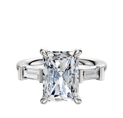 A 14K white gold engagement ring featuring three stones: a center stone flanked by east/west baguette side stones, totaling 0.125TCW, set on a polished band against a white background.