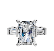 The 14K White Gold 3-Stone Baguette East/West Side Stones 0.25TCW Engagement Ring features a radiant-cut center stone with two baguette side diamonds, shown on a plain white background.
