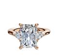 The 14K Rose Gold 3-Stone Trillion Side Stones 0.125TCW Engagement Ring features a radiant-cut center diamond with two triangular side stones, displayed on a plain white background.