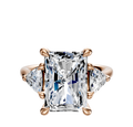 The 14K Rose Gold 3-Stone Trillion Side Stones 0.25TCW Engagement Ring features a rectangular center stone with two triangular side stones, all set on a polished rose gold band.