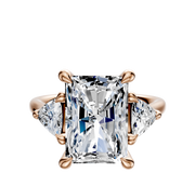 The 14K Rose Gold 3-Stone Trillion Side Stones 0.25TCW Engagement Ring features a rectangular center stone with two triangular side stones, all set on a polished rose gold band.