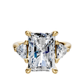 The 18K Yellow Gold 3-Stone Engagement Ring features a central radiant-cut diamond with two trillion side stones (0.25TCW), each set in gold prongs against a plain white background.