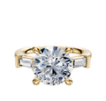 An 18K Yellow Gold 3-Stone Baguette East/West Side Stones 0.125TCW Engagement Ring, featuring a round center stone with two rectangular baguette side stones, is displayed against a plain white background.