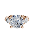 The 14K Rose Gold 3-Stone Pear Side Stones 0.25TCW Engagement Ring features a central round diamond accented by two pear-shaped side diamonds, all set in an elegant four-prong setting.