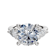 The 14K White Gold 3-Stone Engagement Ring features a round center stone accented by two pear-shaped side stones (0.25TCW), presented on a white background.