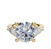 The 14K Yellow Gold 3-Stone Pear Side Stones 0.25TCW Engagement Ring showcases a round brilliant center diamond flanked by two pear-shaped side stones, set against a white background.