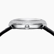 The 39MM Swiss Made Stainless Steel Watch with Diamonds showcases a round diamond-encrusted bezel, mother-of-pearl dial with silver numerals, and a black leather strap, elegantly set against a plain white background.