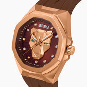 The 42MM Swiss Made 18K Rose Gold Signature Panther Automatic Watch features a brown rubber strap, brown dial with a geometric panther face, diamond markers, green gemstone eyes, and the EARLY name for timeless elegance.